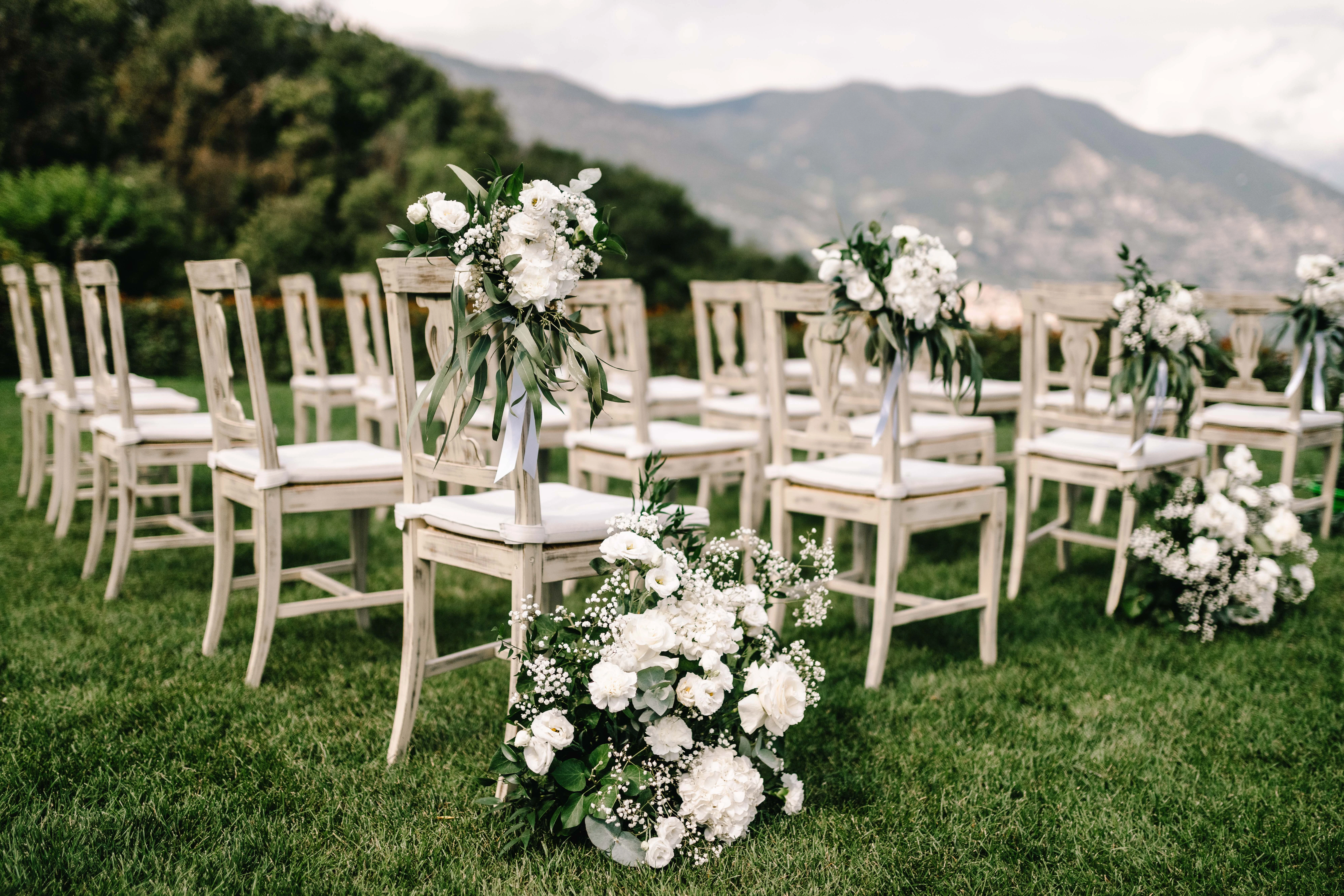 Allestimento cerimonia all'aperto con sedie bianche e fiori nel giardino lago Iseo
