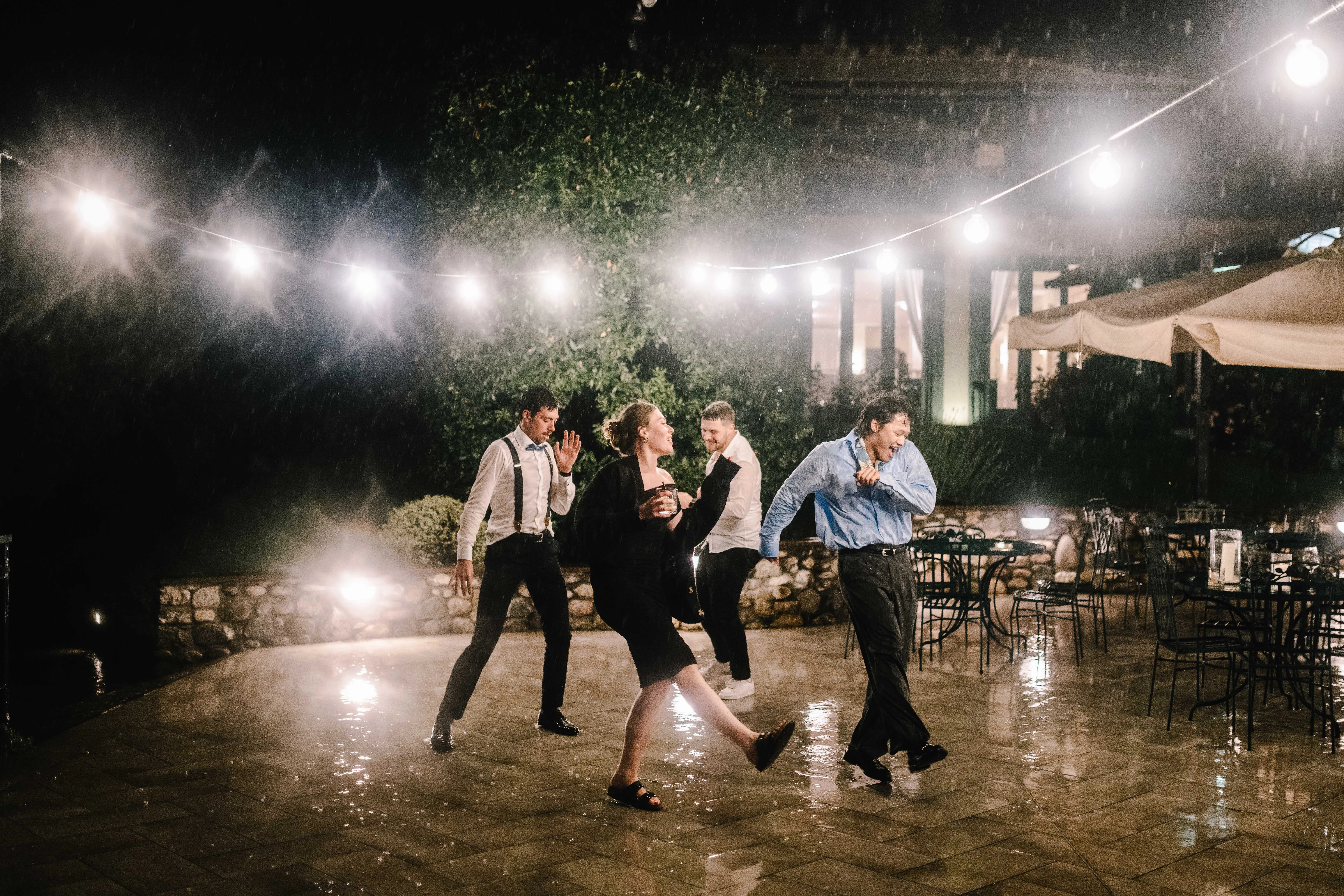 Ospiti che ballano nella terrazza esterna notturna con luci durante matrimonio Franciacorta